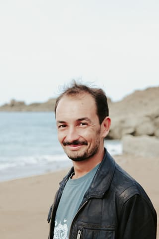 Portrait de Hugo Letellier, souriant, au bord de la mer devant des rochers.