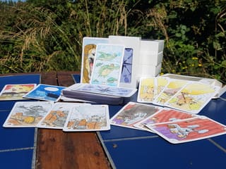 Les cartes du Tarot de Marseille et leur boîte, posées sur une table en extérieur.